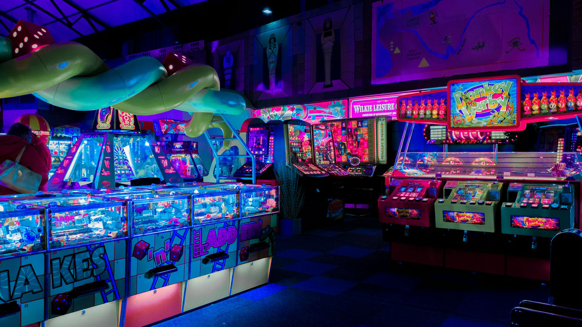 Laser Game playroom with multiple arcade machines. The atmosphere is dimly lit with neon-style colors.