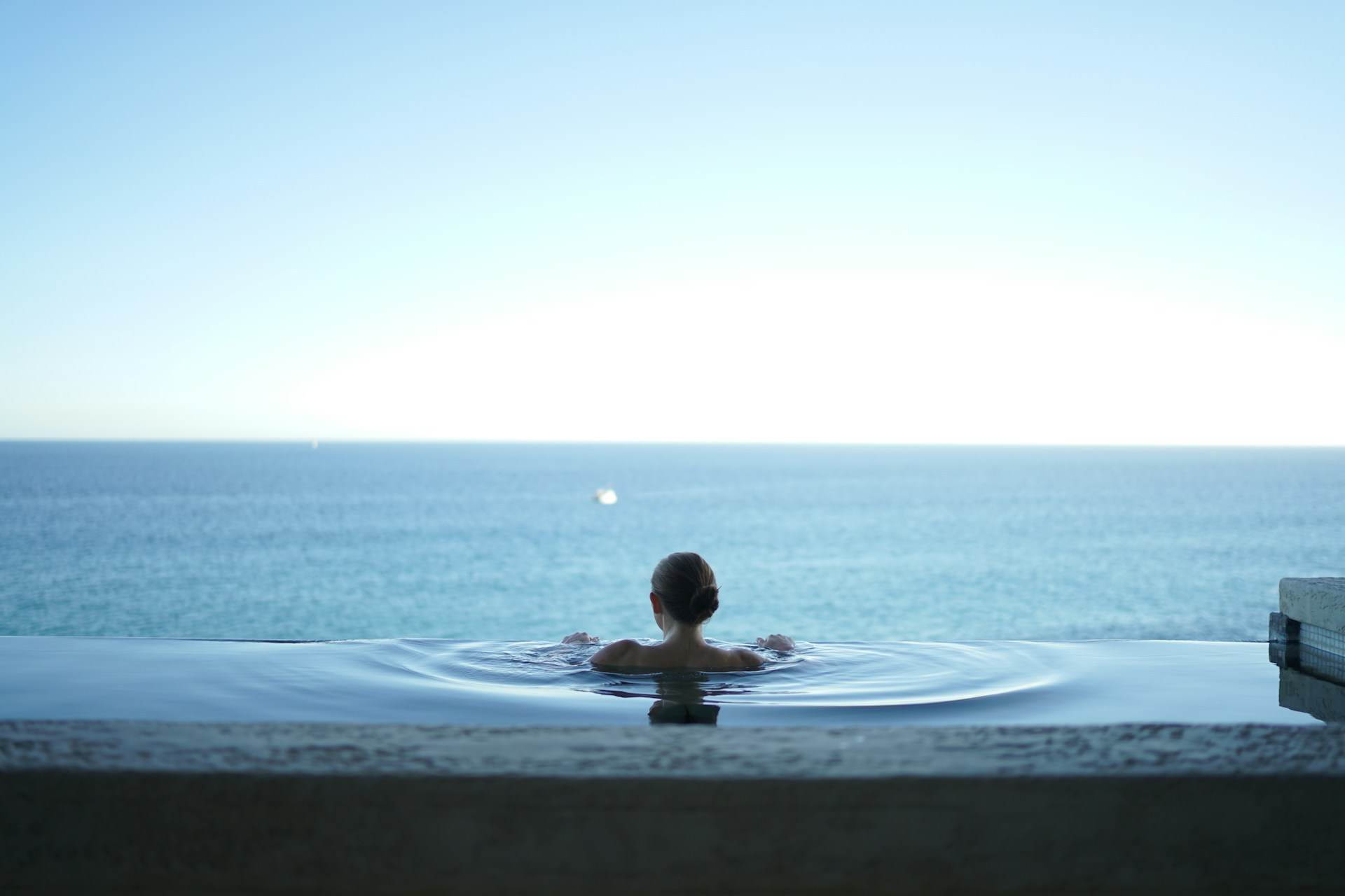 A woman in an outdoor pool with a view of the lake.